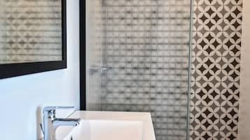Un baño moderno con un lavamanos blanco, un espejo y baldosas estampadas en las paredes.