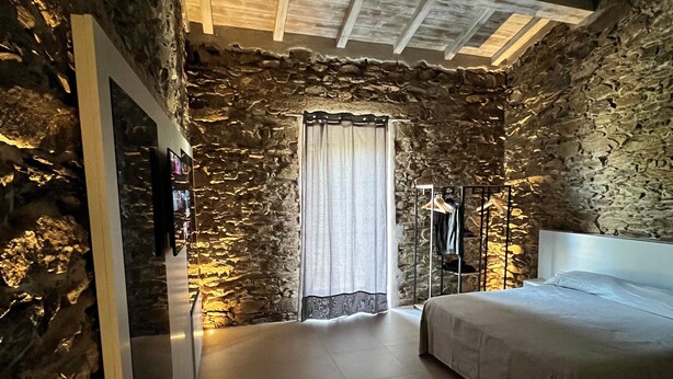 Ein Schlafzimmer mit Steinwand, Bett, Kleiderschrank und Spiegel.