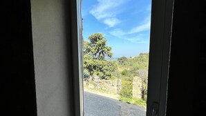 Ein Zimmer mit großem Fenster und Blick auf eine Straße und Grünflächen.