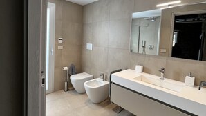 Ein modernes Badezimmer mit zwei Bidets, einem großen Spiegel und einem Waschtisch.