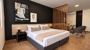 Habitación de hotel moderna con una cama grande, una mesita de noche, un escritorio con silla y un ventanal amplio.