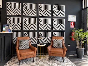 Una habitación con dos sillones de cuero, una mesita redonda y un suelo con diseño.