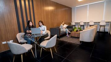 A modern waiting area with a wooden accent wall, a round table with chairs, and a sofa.