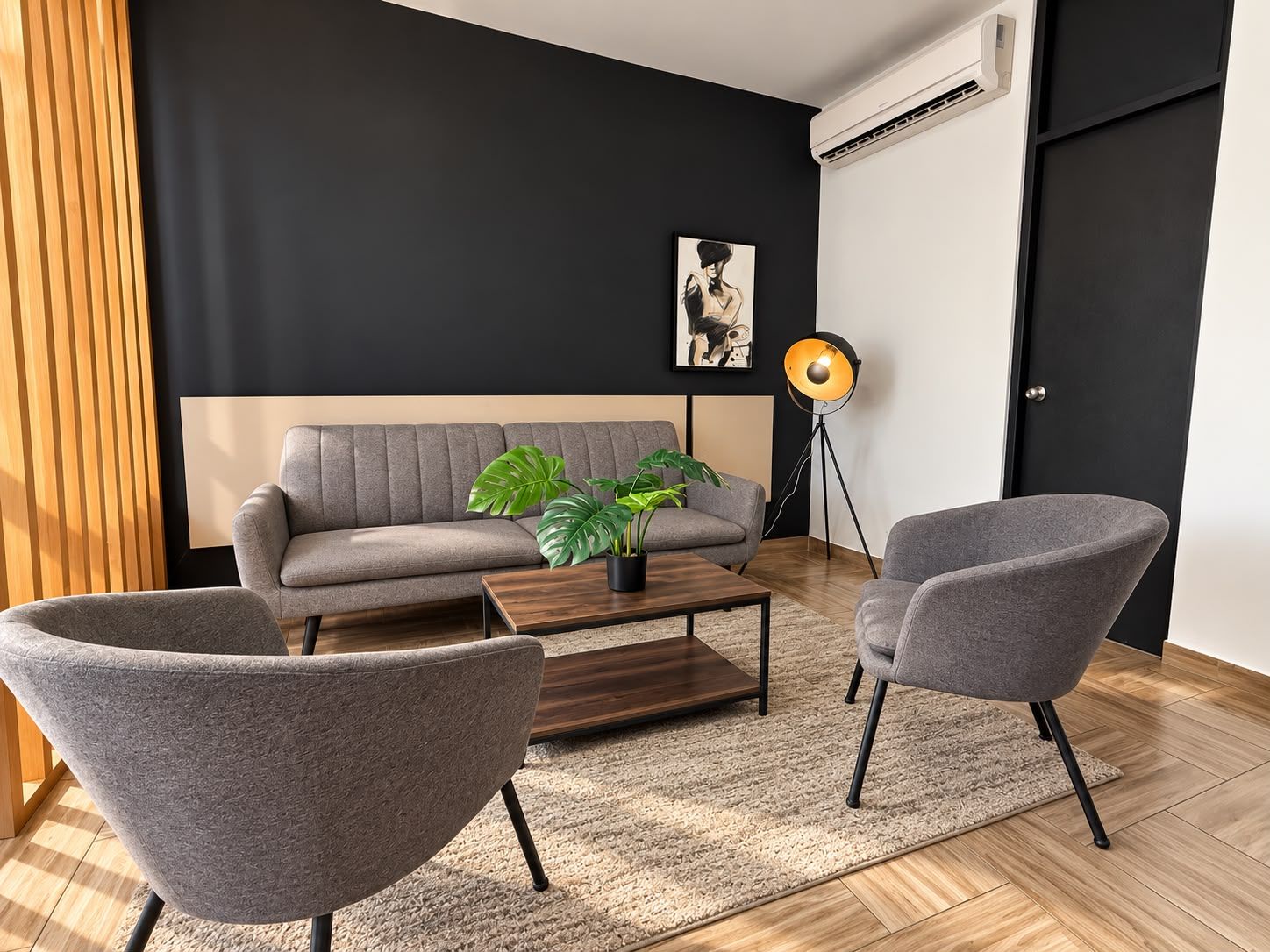Una sala de estar moderna con un sofá gris, dos sillones, una mesa de centro, una planta en maceta, una lámpara de pie y un cuadro en la pared.