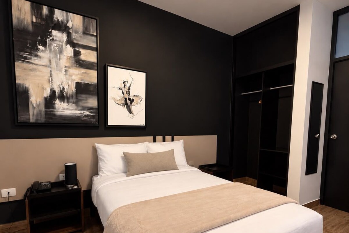 Un dormitorio moderno con una cama grande, una mesita de noche, una obra de arte colgada en la pared y un armario.