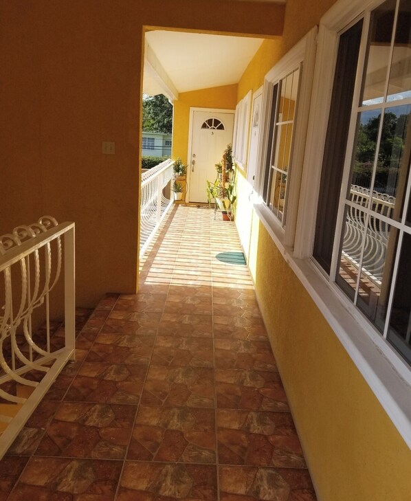 A corridor with tiled flooring, a white railing, and a door marked with the number 5.
