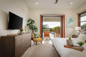 A bedroom with a bed, a TV, a desk, and a view of the outdoors.