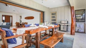 A dining area with wooden furniture, a ceiling fan, and a view of the kitchen. - Waikoloa Luxe Golf Estate w/ Hilton Pool passes, Gameroom (Puako)
