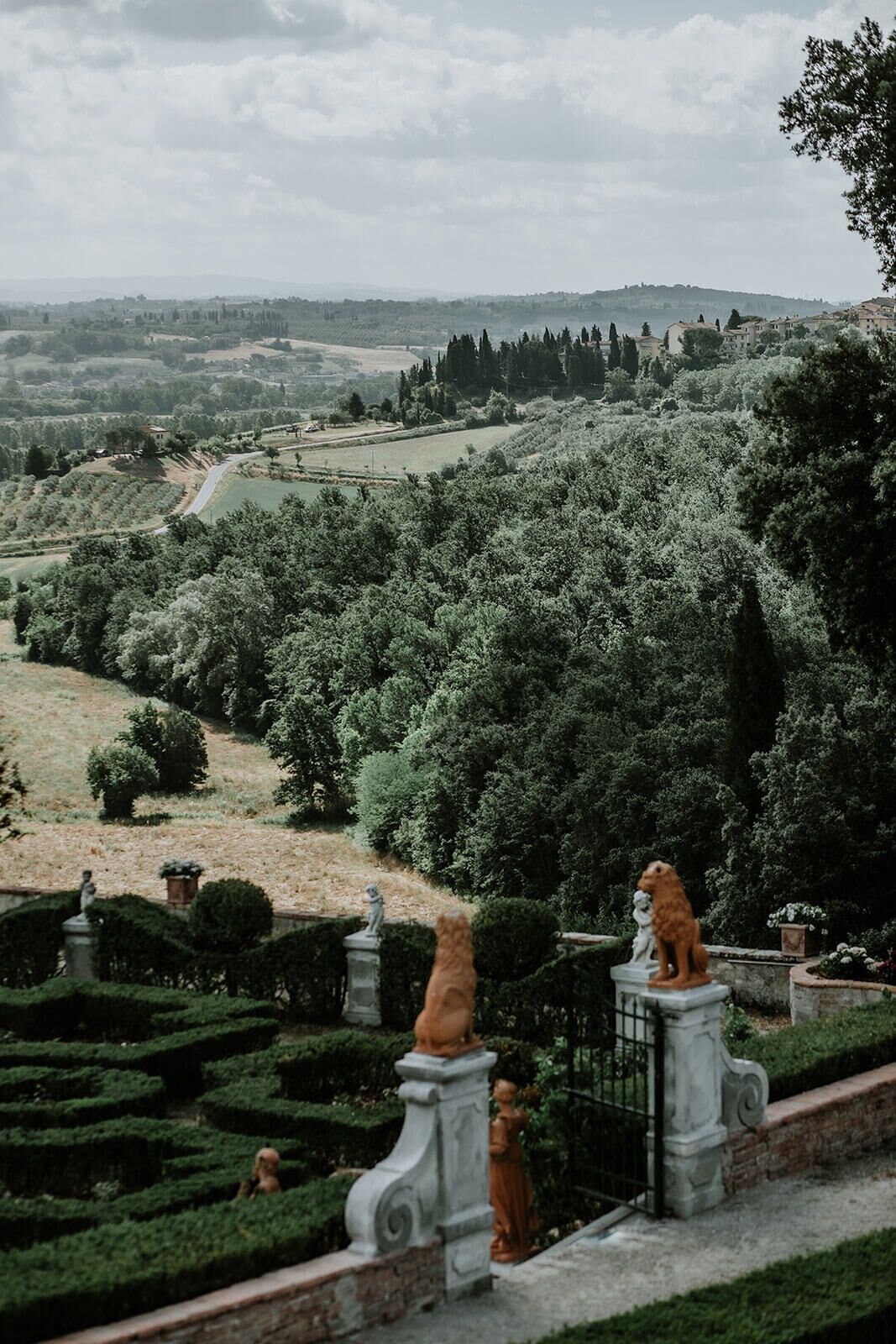 Un jardín ajardinado con estatuas y setos, con vistas a un paisaje montañoso.