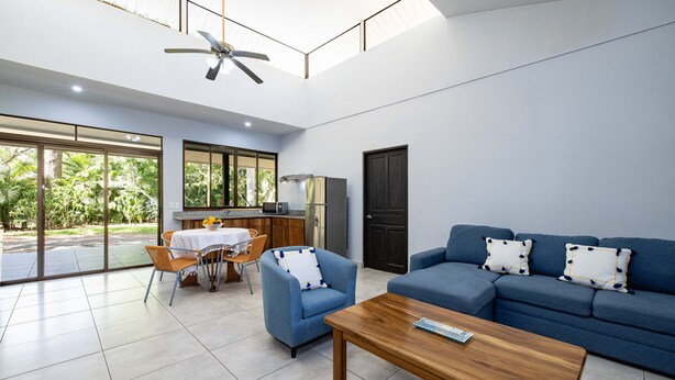 A spacious living area with a blue sofa, a wooden coffee table, and a dining table with chairs. - CASA CARAO POTRERO -100 Metros de la Playa (Provincia de Guanacaste)