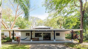 A modern house with a covered porch, large windows, and a hammock. - CASA CARAO POTRERO -100 Metros de la Playa (Provincia de Guanacaste)