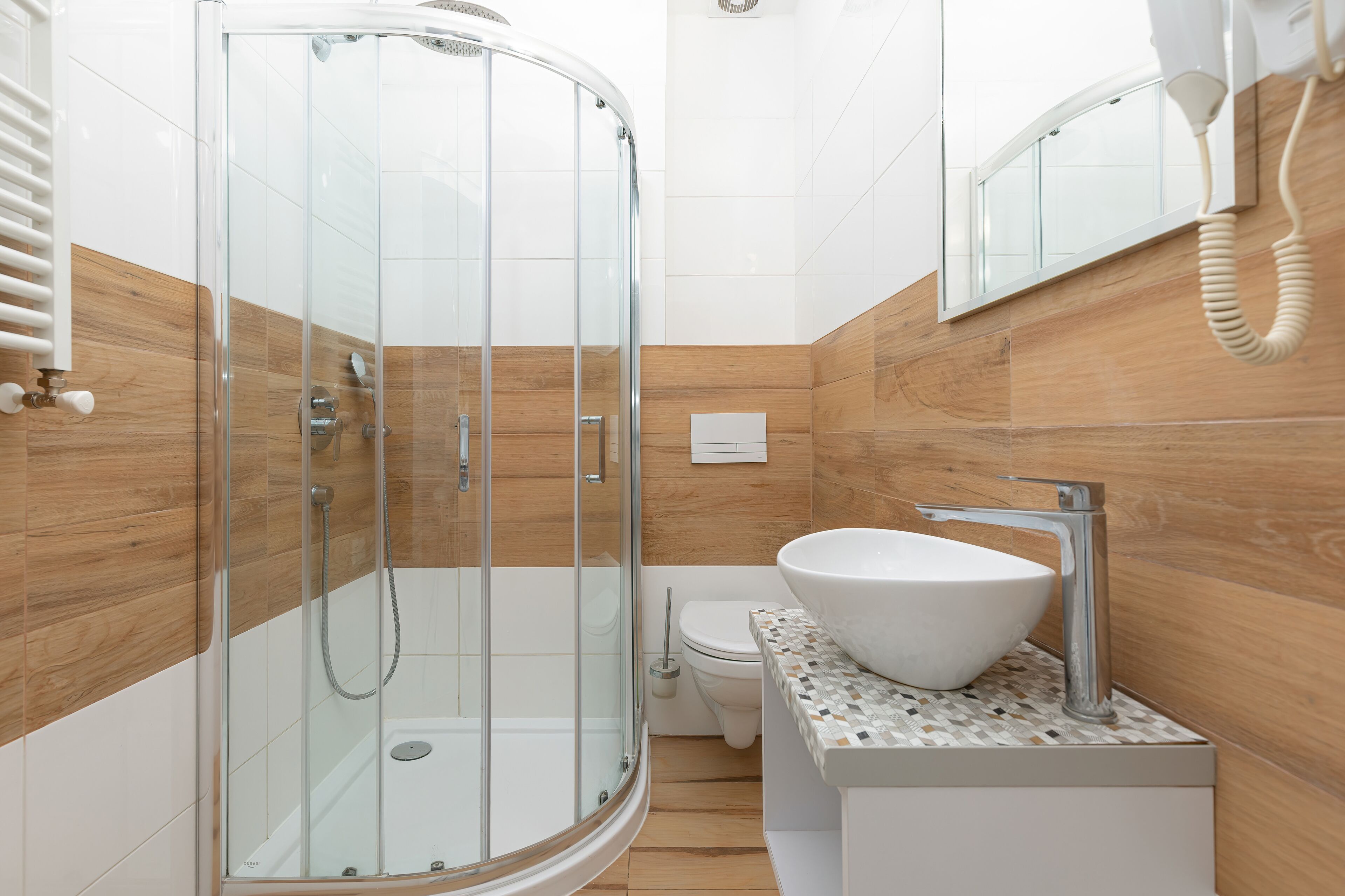 A modern bathroom with a glass-enclosed shower, a white sink, and a wooden wall panel.