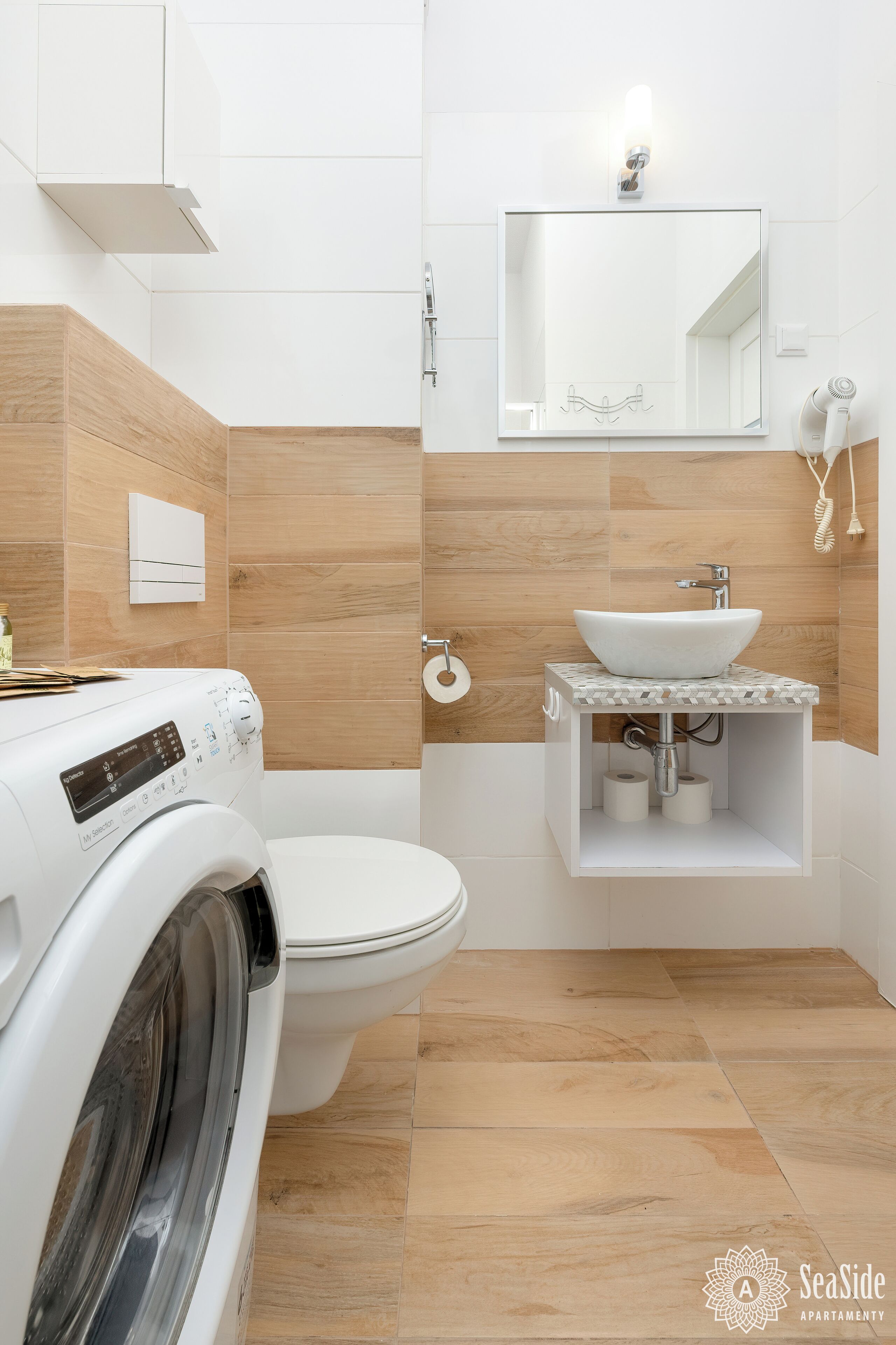 Un bagno moderno dotato di lavatrice a incasso, servizi igienici e lavandino con specchio sopra.