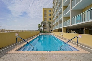 Une piscine avec un panneau indiquant qu’il est interdit de plonger, un indicateur de profondeur indiquant 3 pieds, et un bâtiment avec des balcons en arrière-plan.