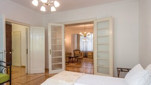 Un dormitori amb llit, cadira i escriptori. Les portes estan obertes cap a altres habitacions.