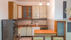 Cuina compacta amb nevera, fogó, rentapelats i taulell de fusta.