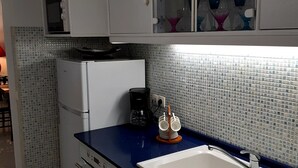 Een keuken met een blauw aanrecht, witte kastjes en een witte spoelbak, plus een magnetron.