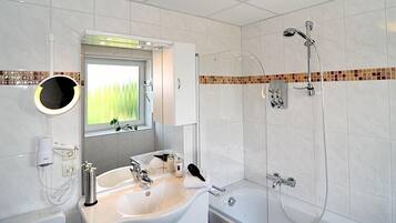 A modern bathroom with a sink, mirror, and shower.