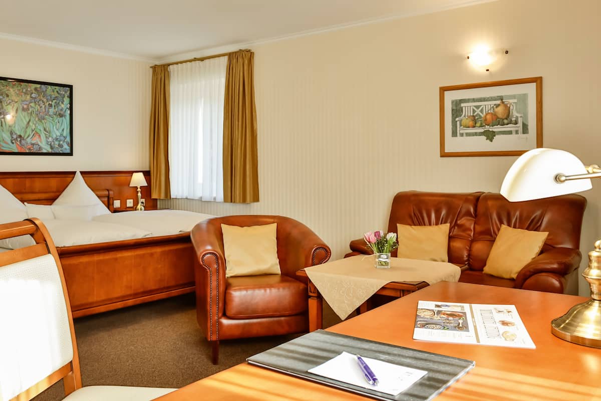 A hotel room with a bed, a sofa, a desk, and a chair.