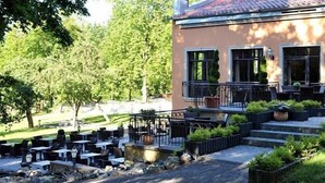 Un espace extérieur aménagé avec des tables et des chaises, un escalier menant à un balcon et des plantes en pot.