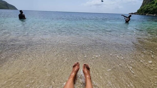 A beach scene with clear water and a person lying on the sand. - Spacious hideaway with ocean views and fine eatery (00000)