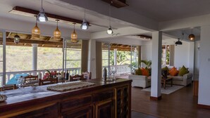 A spacious living area with a large window, a wooden dining table, and a bar area. - Spacious hideaway with ocean views and fine eatery (00000)