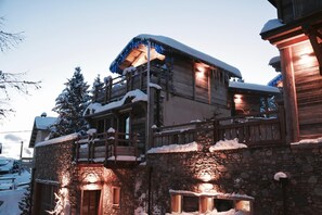 Un edificio de piedra con un nivel superior de madera, barandillas de madera y un tejado cubierto de nieve.