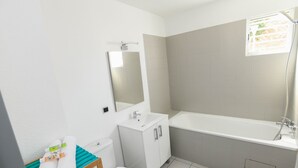 Une salle de bain comprenant des toilettes, un lavabo, un miroir et une baignoire.