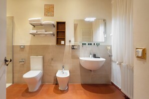 Une salle de bain comprenant des toilettes, un bidet, un porte-serviettes, un lavabo et un miroir.