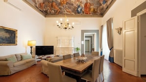 Un ampio soggiorno con tavolo da pranzo in legno, divani color beige e un grande quadro appeso al muro.