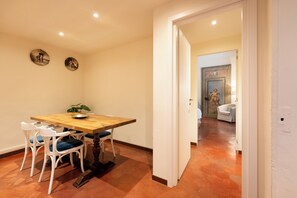 Un coin repas avec une table en bois et des chaises blanches, une petite plante posée sur la table et deux assiettes décoratives accrochées au mur.