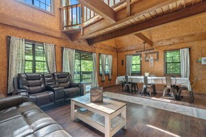 A spacious living area with a leather sofa, a wooden coffee table, and a dining table with chairs.
