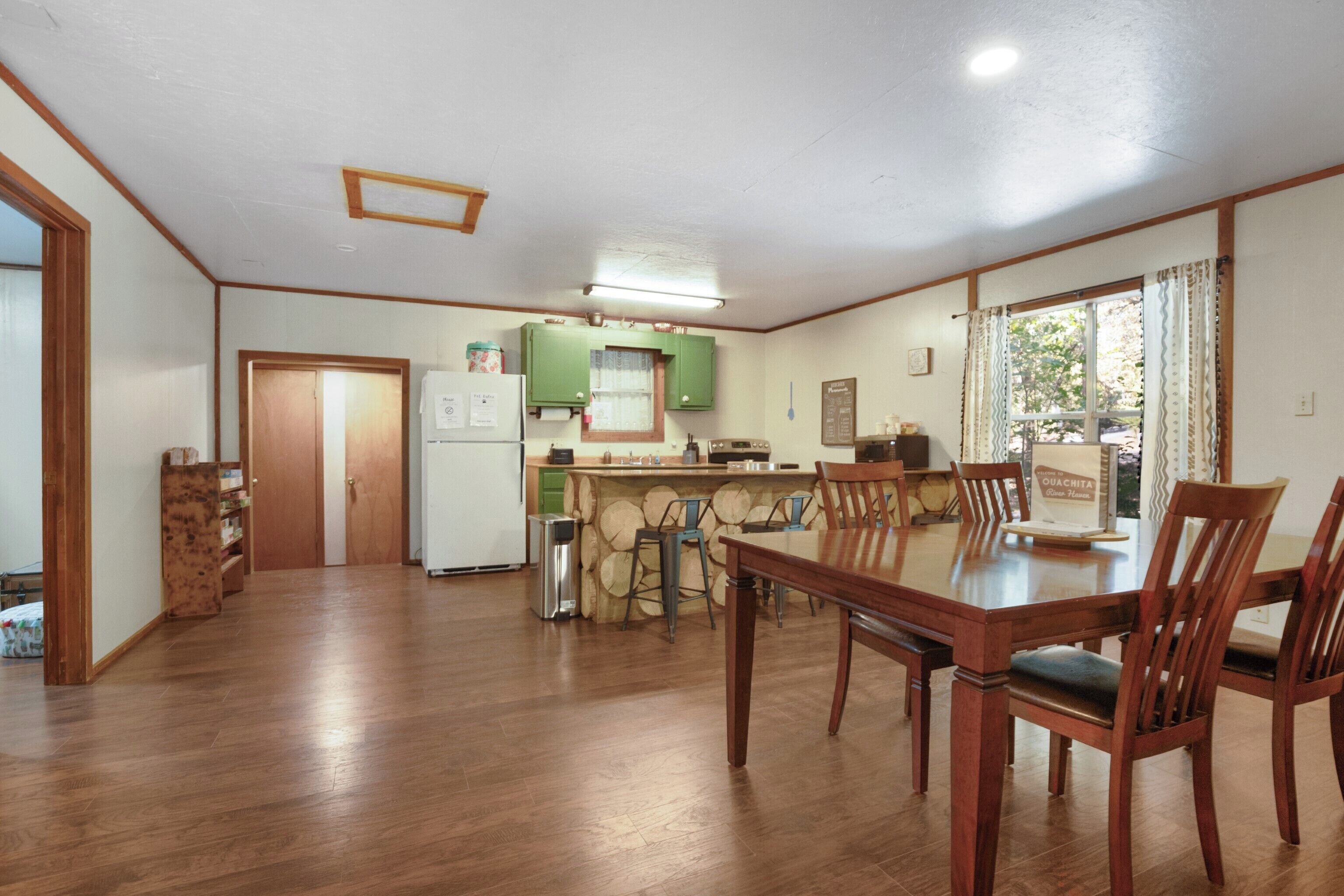 A spacious kitchen with wooden cabinets, a dining table with chairs, and a view of the outdoors through a window.