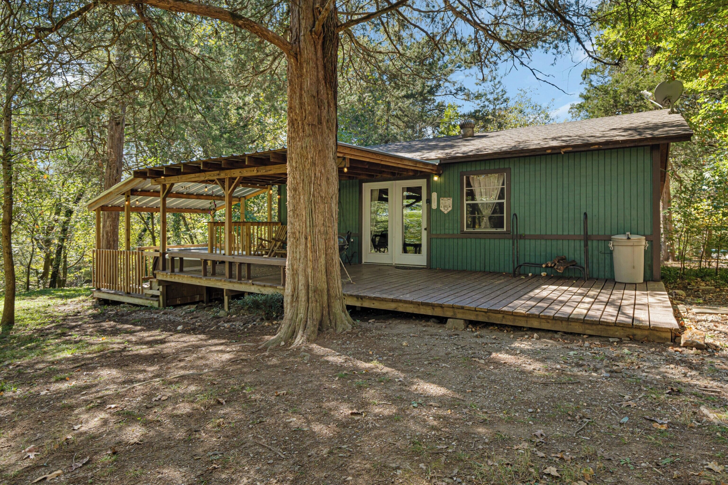 A small cabin with a wooden deck, a covered porch, and a satellite dish.