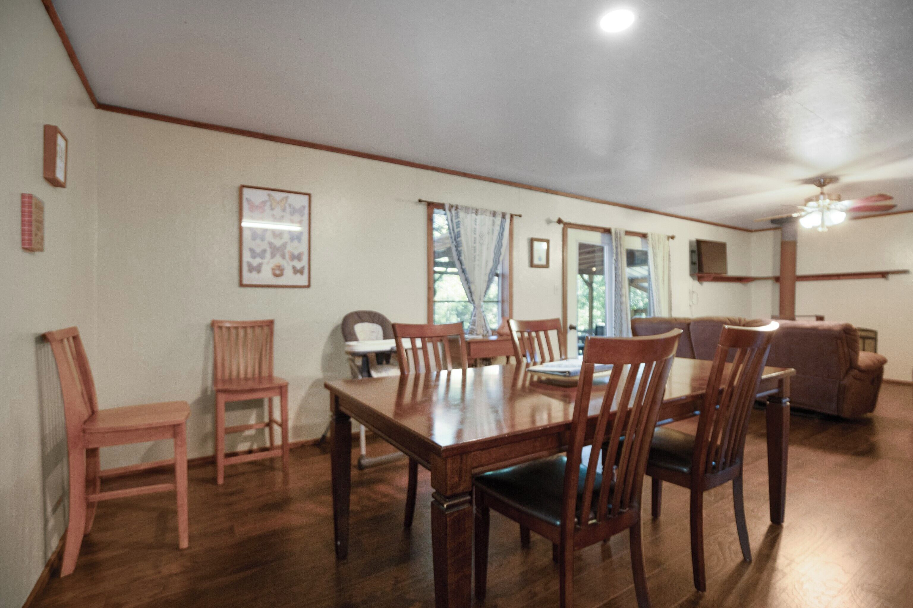 A dining area with a wooden table and chairs, a sofa, and a ceiling fan.