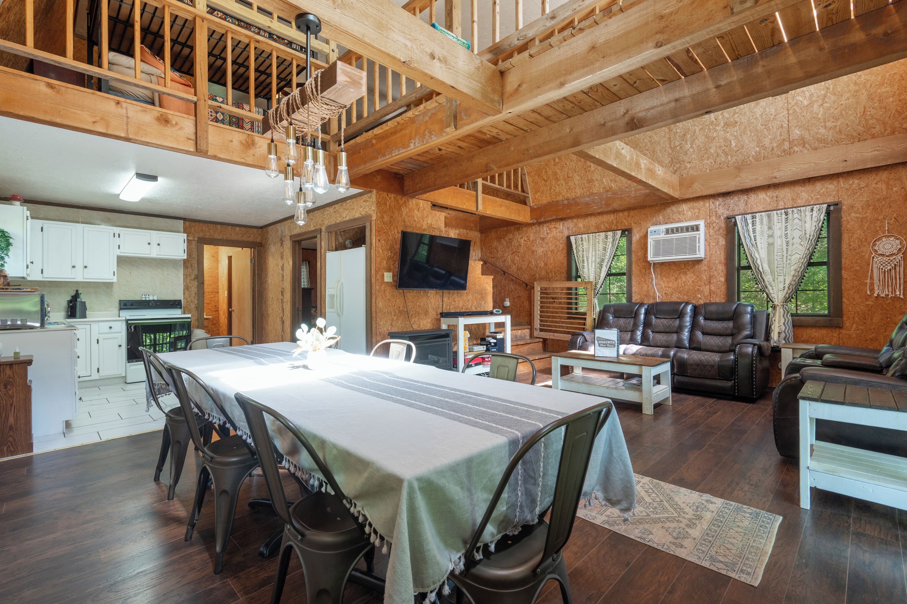 A spacious living area with a dining table, chairs, a sofa, and a TV.