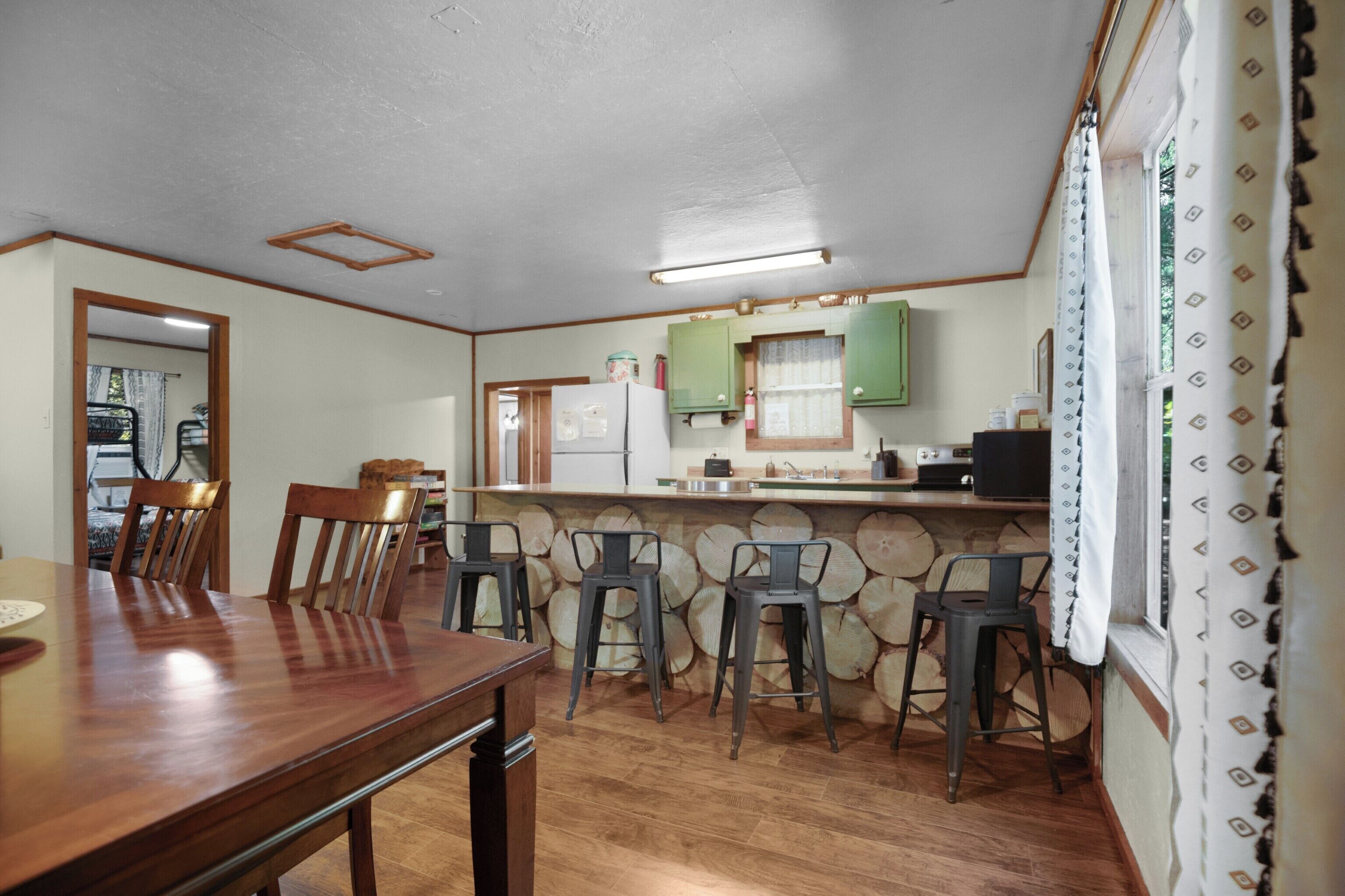 A kitchen with wooden chairs, a dining table, and a counter with green cabinets.