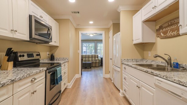 A kitchen with white cabinets, a stainless steel oven, a microwave, and a granite countertop.