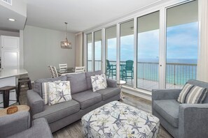 A spacious balcony with a view of the ocean, a gray sofa, and a matching armchair.