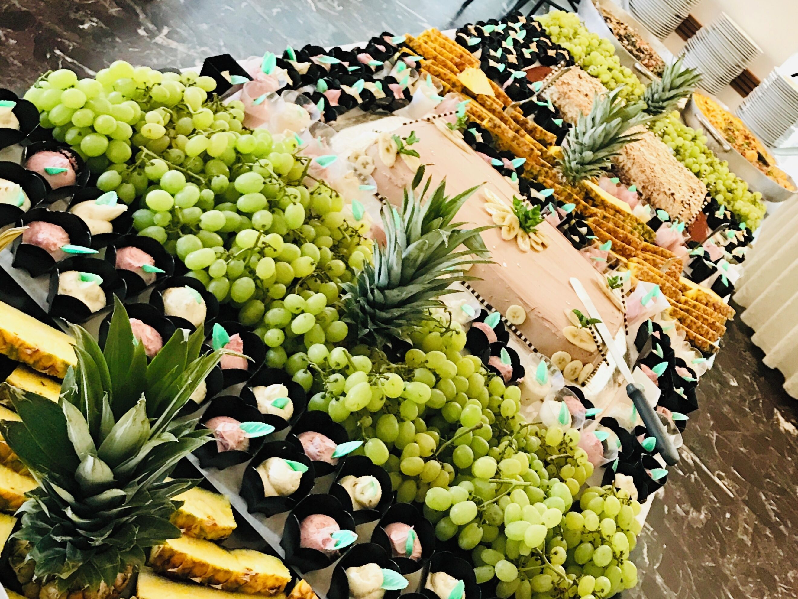 A buffet table with various food items including grapes, pineapple, and waffles.