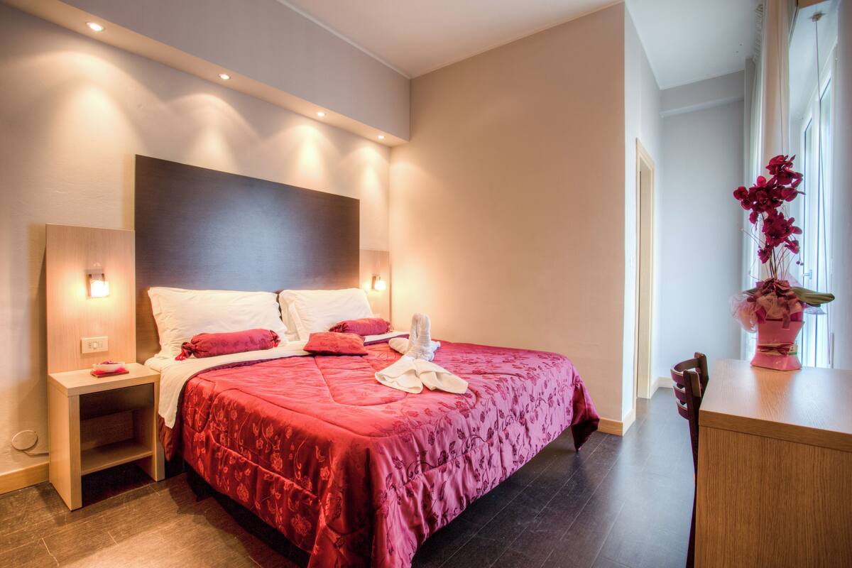 Un dormitorio moderno con una cama grande, mesitas de noche y una mesita auxiliar.