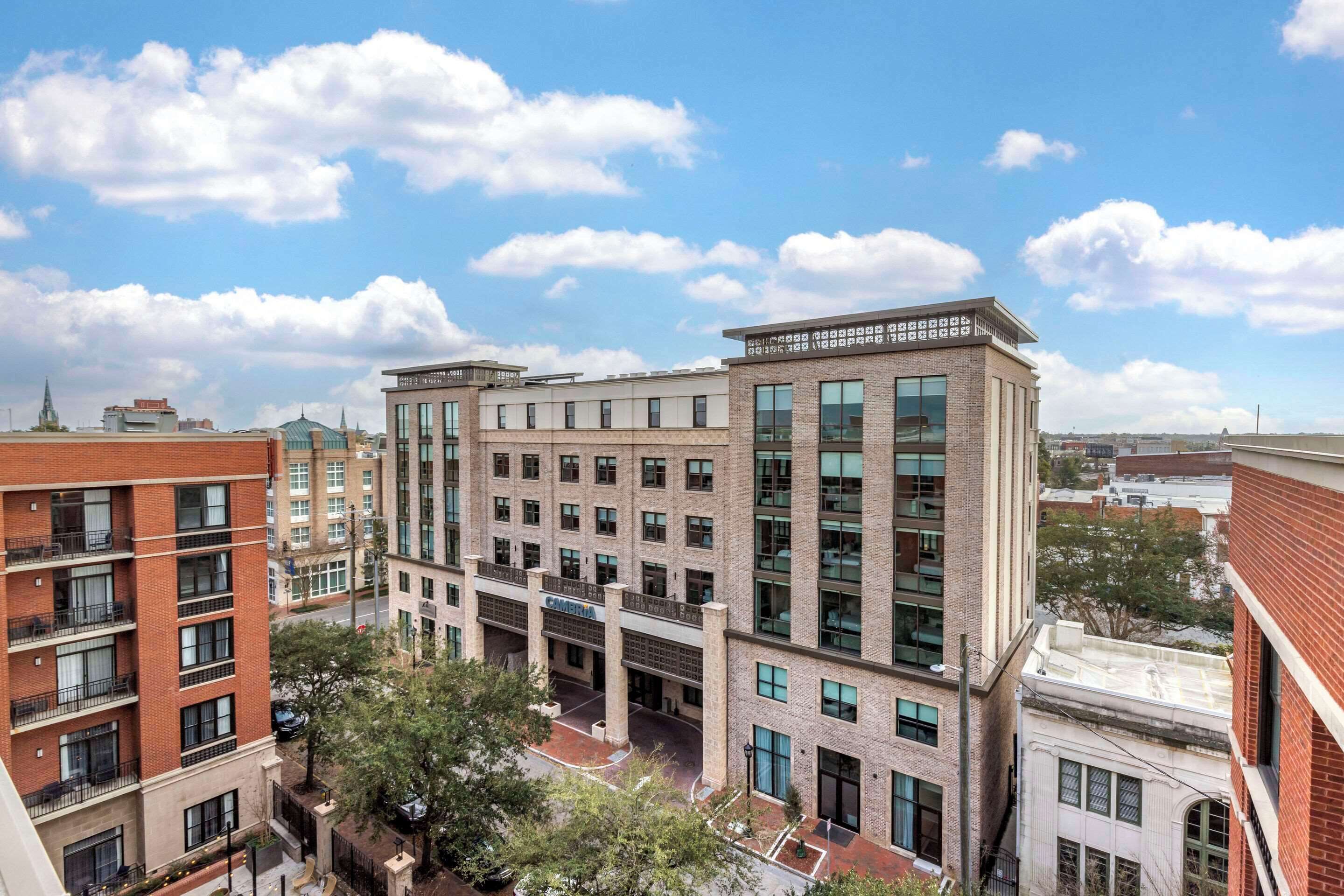 A multi-story hotel with a central courtyard, large windows, and a brick facade.