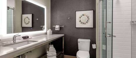 Une salle de bain moderne avec un grand miroir, un lavabo, des toilettes et une douche à parois de verre.