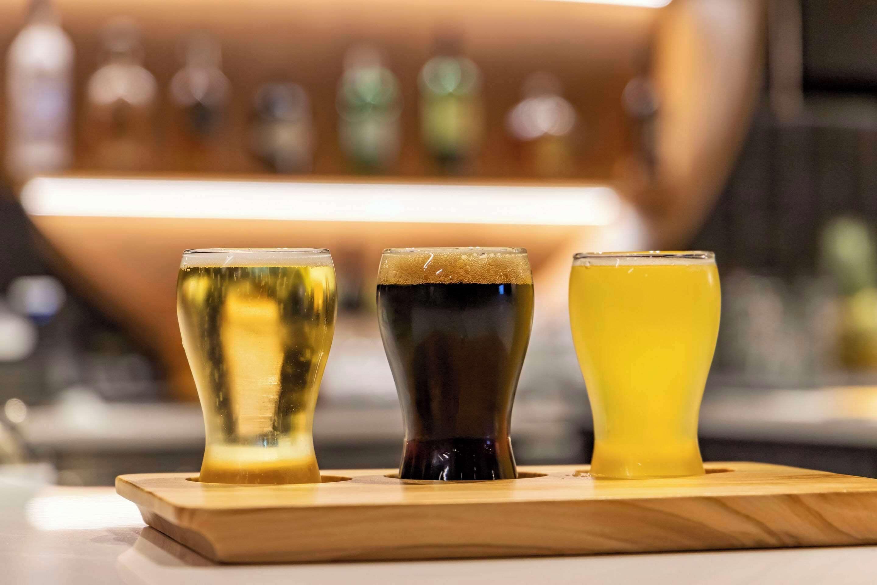 Three glasses of different beverages on a wooden tray.