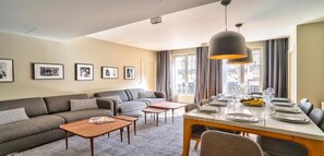 A modern living room with a sofa, coffee table, and dining area set for a meal.