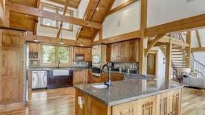 A spacious kitchen with wooden beams, granite countertops, and built-in appliances.