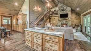 Une cuisine spacieuse avec des meubles en bois, un plan de travail en marbre et une cheminée en pierre.