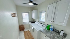 A compact kitchen with white cabinets, a built-in stove, a granite countertop, and a ceiling fan.