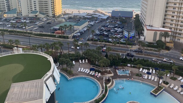 Ein Resort mit mehreren Swimmingpools, einem Parkplatz und Blick auf Strand und Meer.