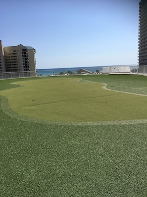 Un parcours de golf offrant une vue dégagée sur l’océan et les immeubles de grande hauteur situés à proximité.
